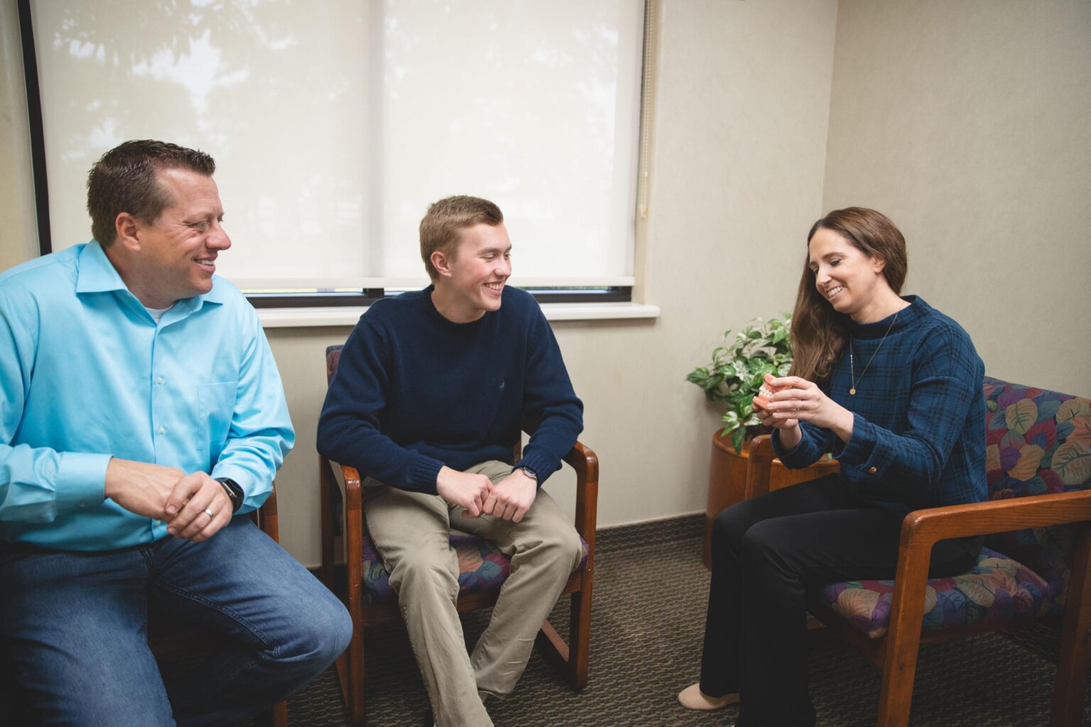 Family orthodontic consultation at Johnston Family Orthodontics in Mont Belvieu, featuring a smiling orthodontist and two patients discussing clear aligners.