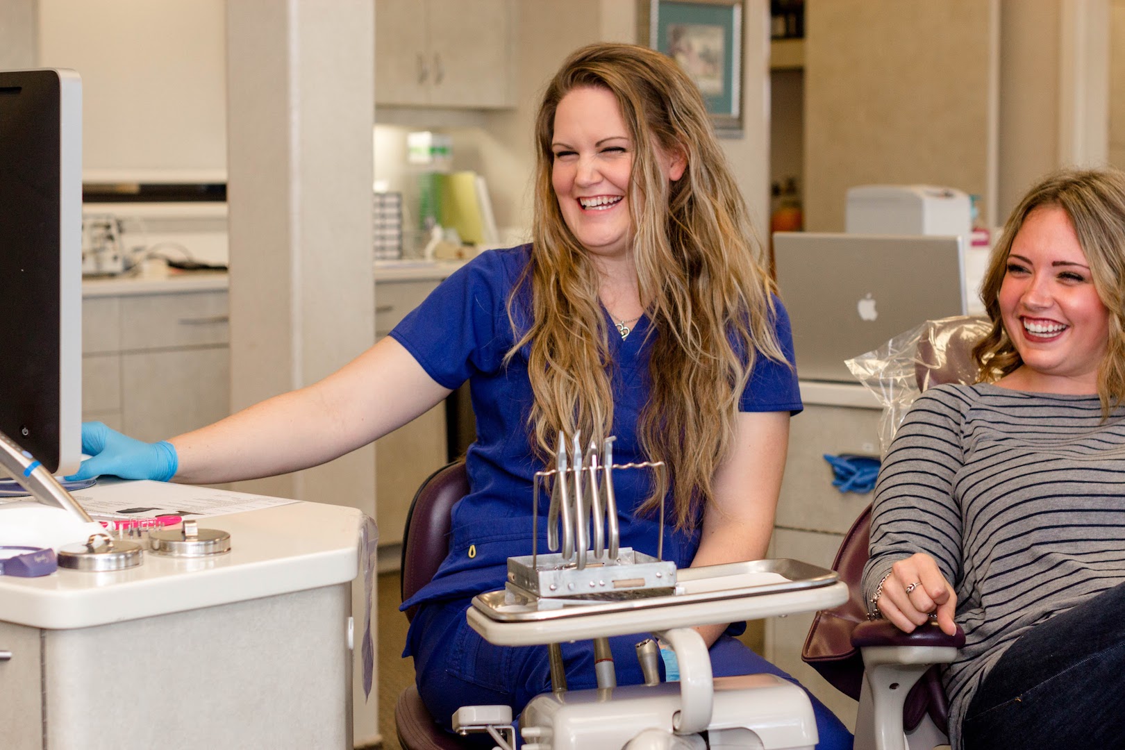 Orthodontist team member smiling and interacting with a patient in a dental office, showcasing personalized care at Johnston Family Orthodontics in Baytown, Texas, emphasizing clear aligners and patient engagement.