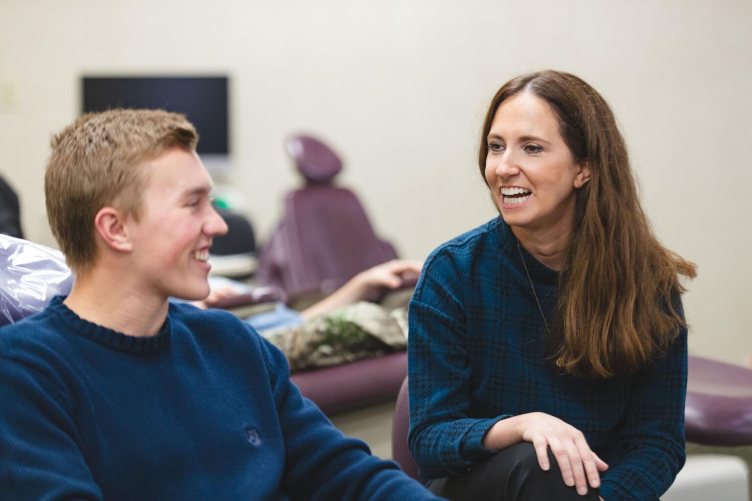 Young patient and orthodontist smiling and engaging in conversation during an orthodontic appointment at Johnston Family Orthodontics, showcasing a welcoming atmosphere for orthodontic care in Mont Belvieu, TX.